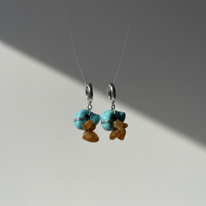 Pair of earrings with turquoise and amber beads on a gray background