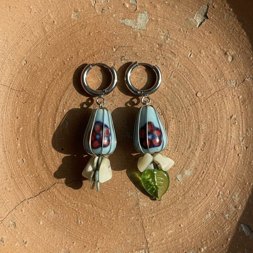 Pair of earrings with teardrop-shaped charms on a textured brown surface