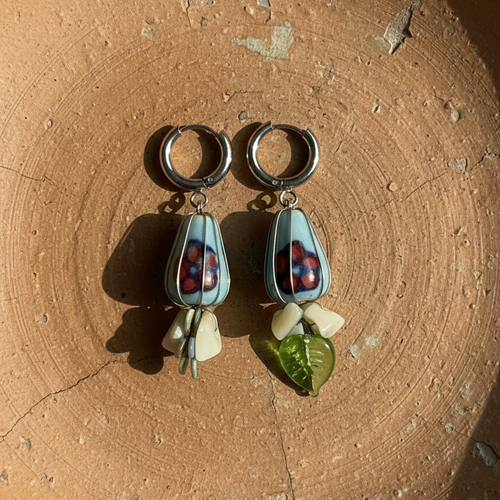 Pair of earrings with teardrop-shaped charms on a textured brown surface