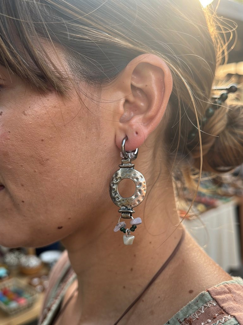 Close-up of a person wearing a silver earring with a blurred background