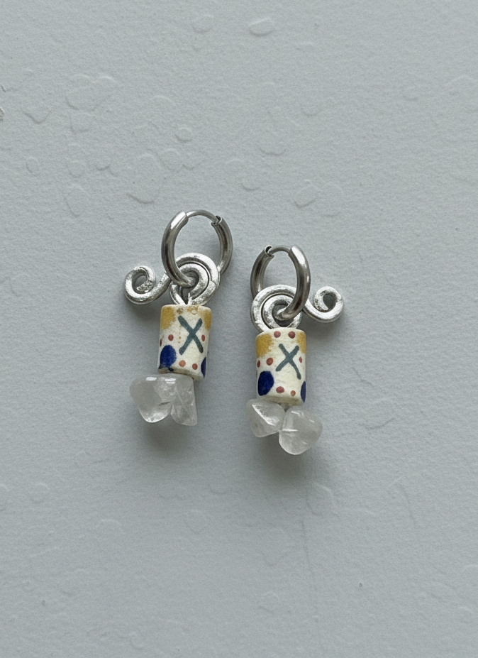 Small silver earrings with colorful beads on a gray background