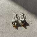 Pair of earrings with ceramic beads on a textured surface