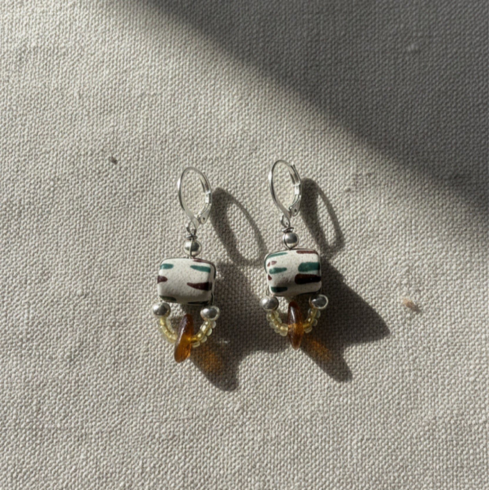 Pair of earrings with ceramic beads on a textured surface