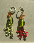 Pair of earrings with coral and bead charms on a neutral background