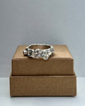 Silver ring on a brown jewelry box against a gray background