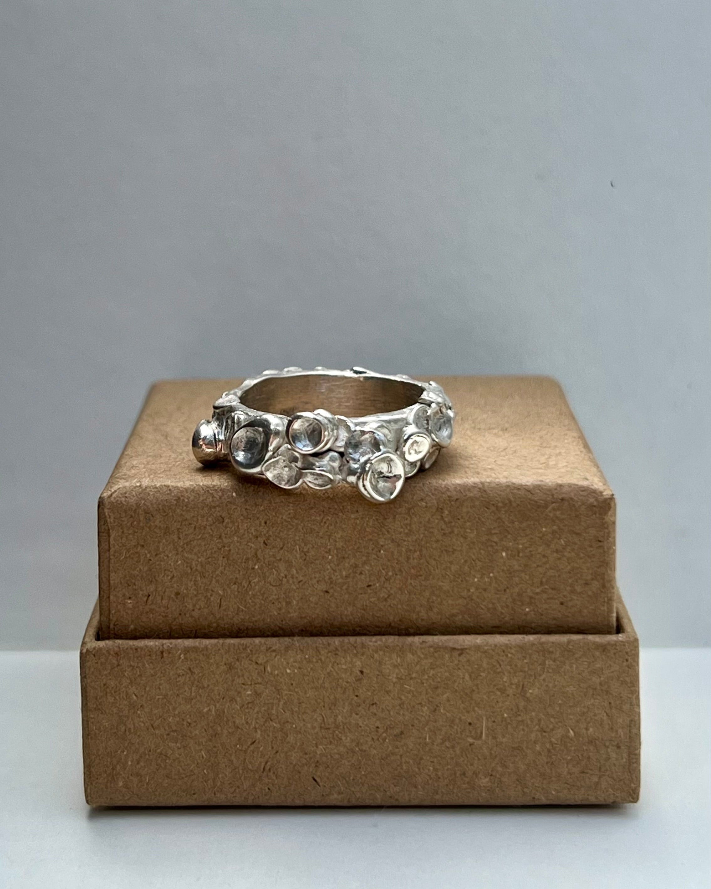 Silver ring on a brown jewelry box against a gray background