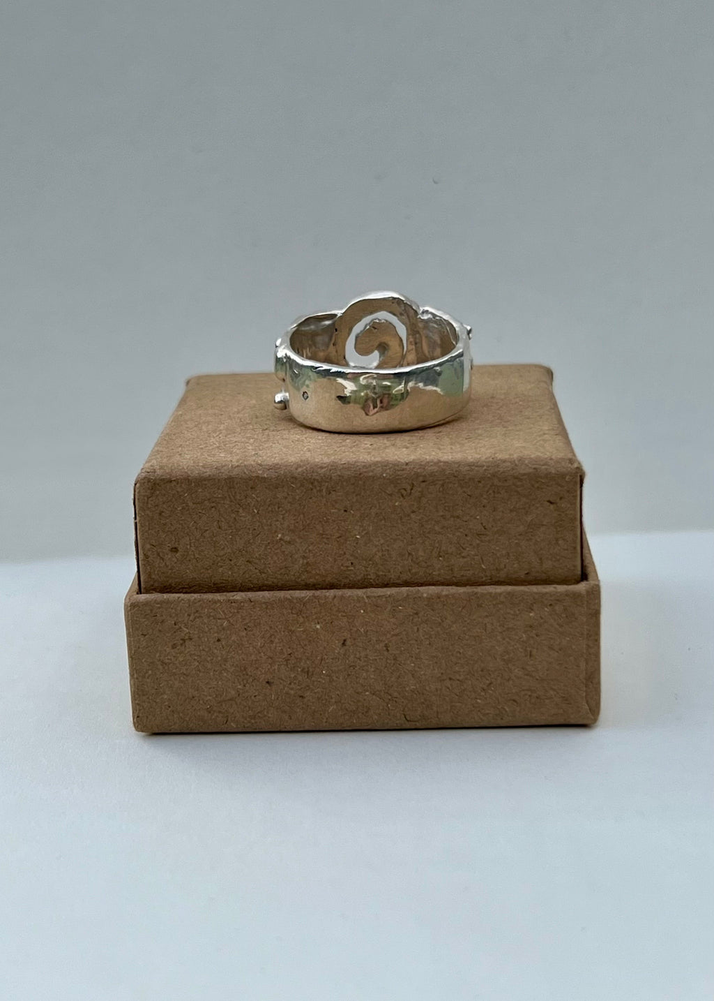 Silver ring on a brown cardboard box against a gray background