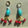 Pair of earrings with turquoise beads and red accents on a gray background