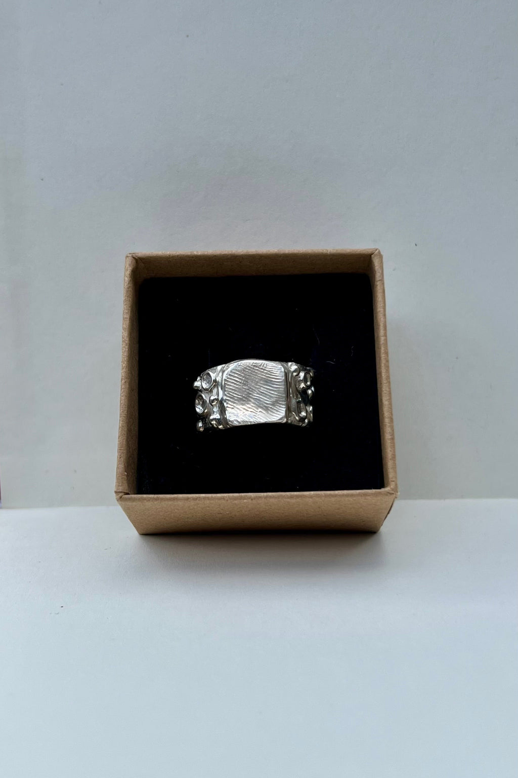 Silver ring in a cardboard box on a white background