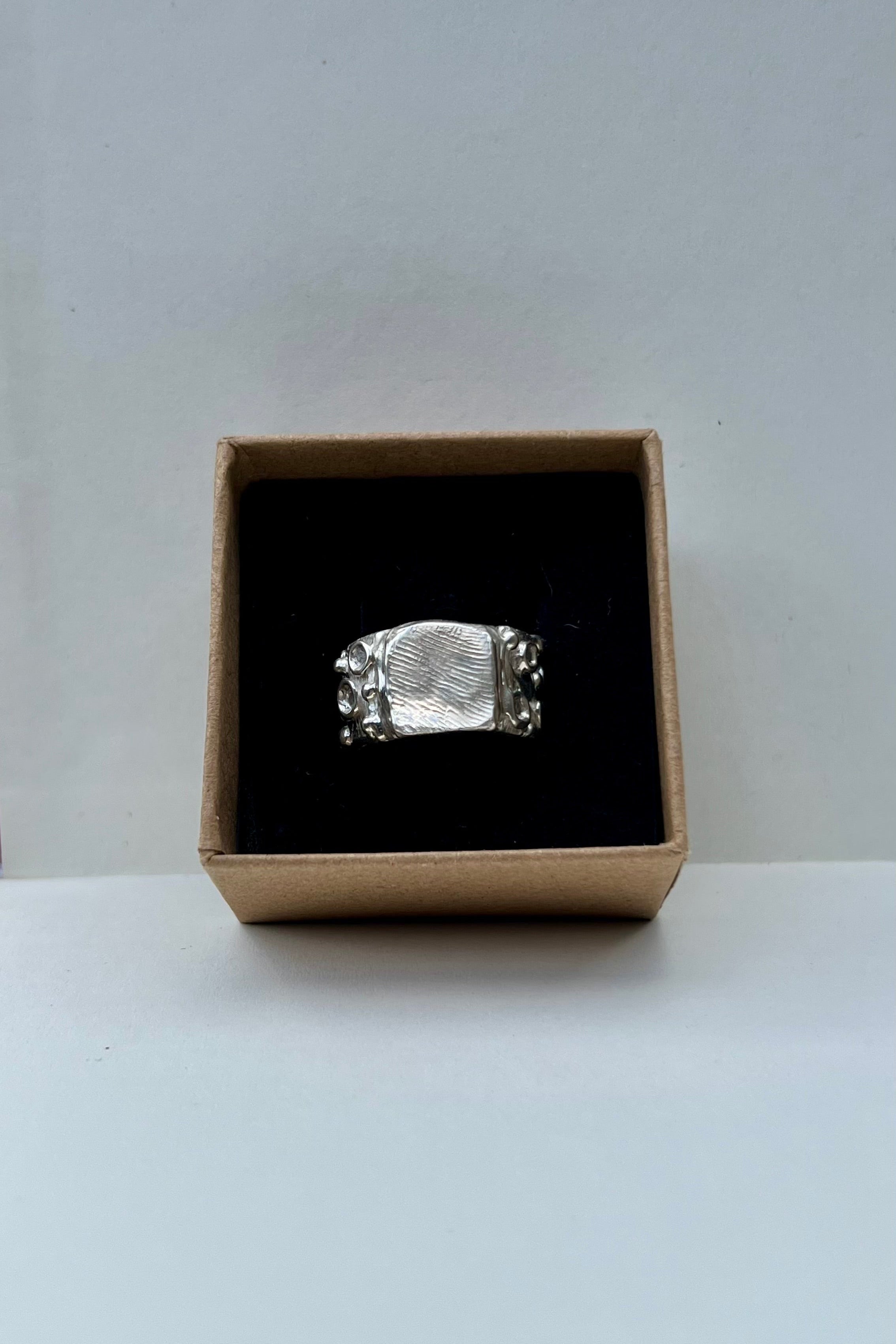 Silver ring in a cardboard box on a white background