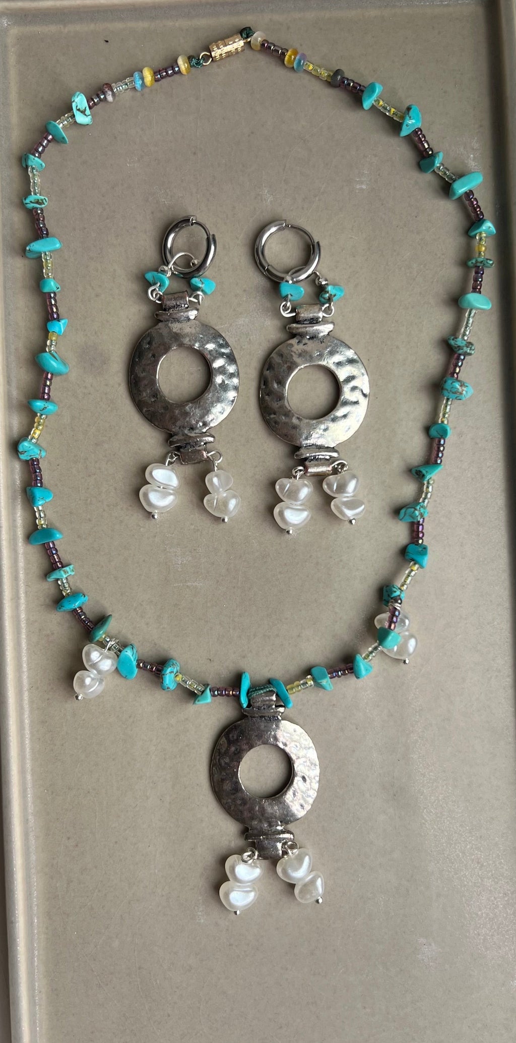 Necklace with silver and turquoise beads on a gray tray