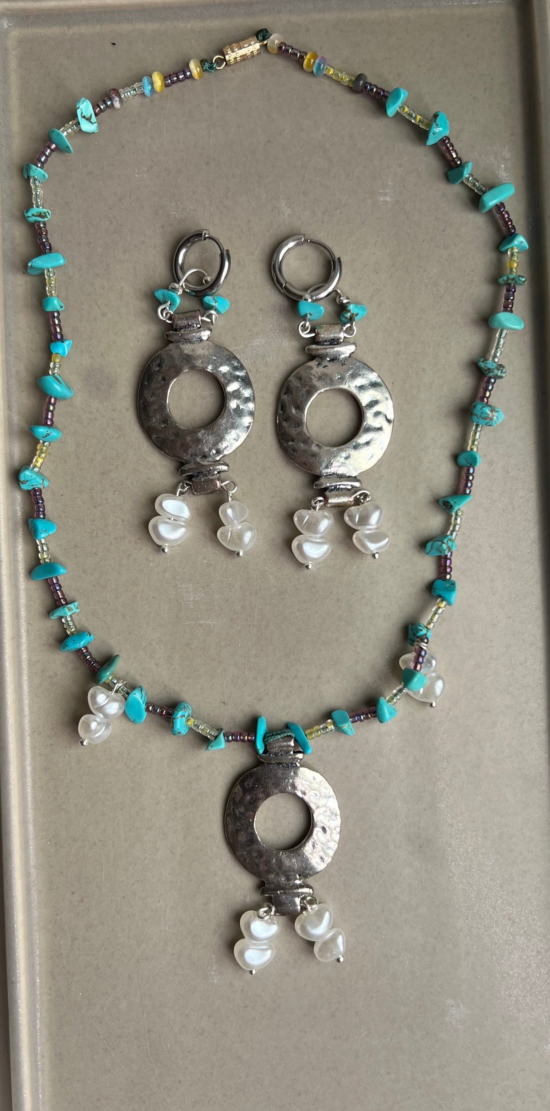 Necklace with silver and turquoise beads on a gray tray