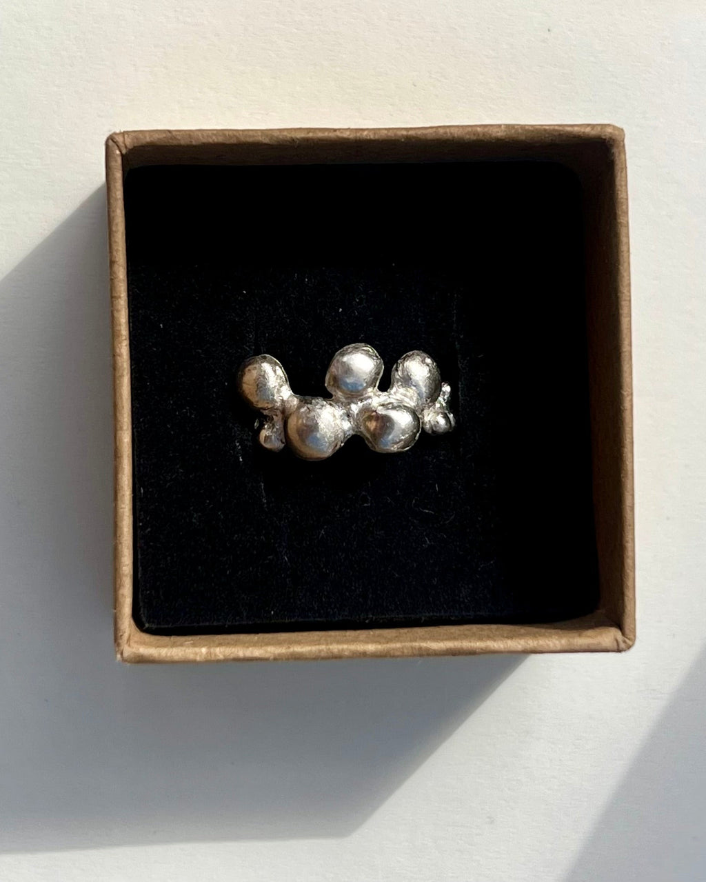 Silver earring in a box on a white surface