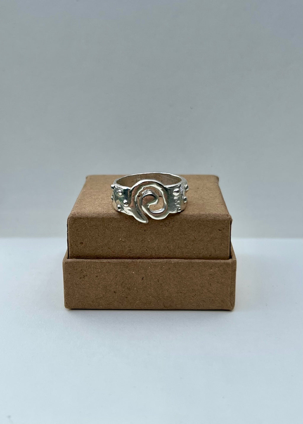 Silver ring on a cardboard box against a gray background