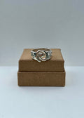 Silver ring on a cardboard box against a gray background