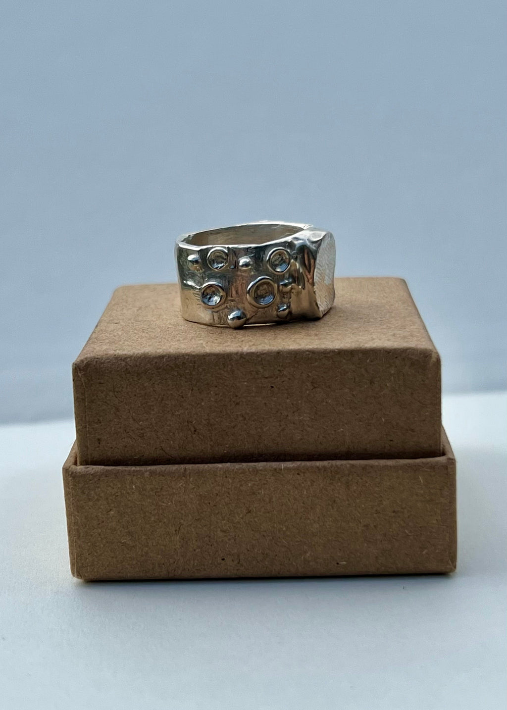 Silver ring on a brown cardboard box against a light gray background