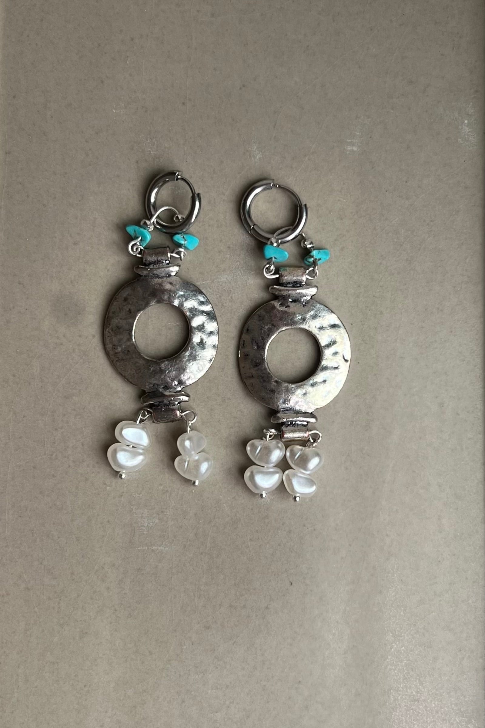 Pair of silver earrings with heart-shaped designs on a gray background