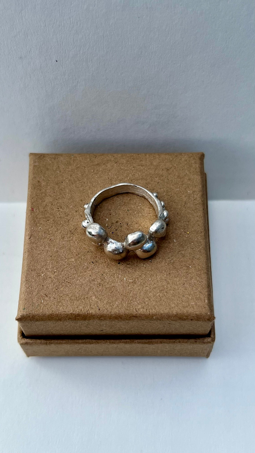 Silver ring on a brown jewelry box with a white background