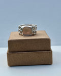Silver ring on a brown box with a light gray background