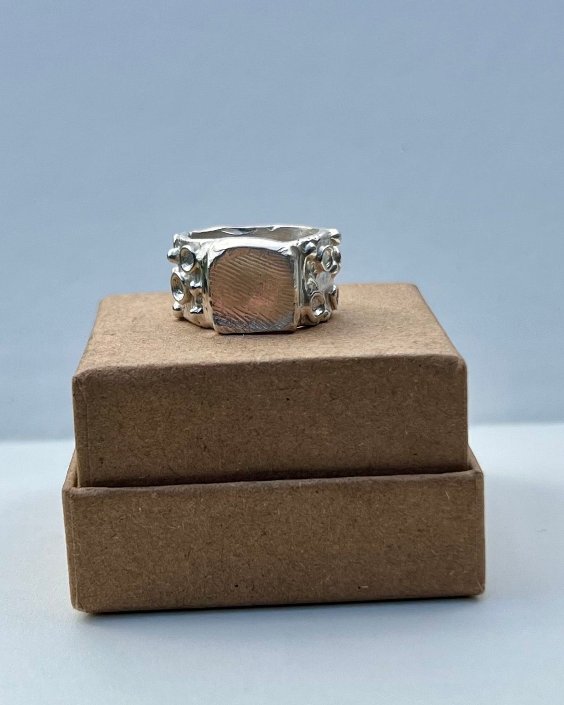 Silver ring on a brown box with a light gray background