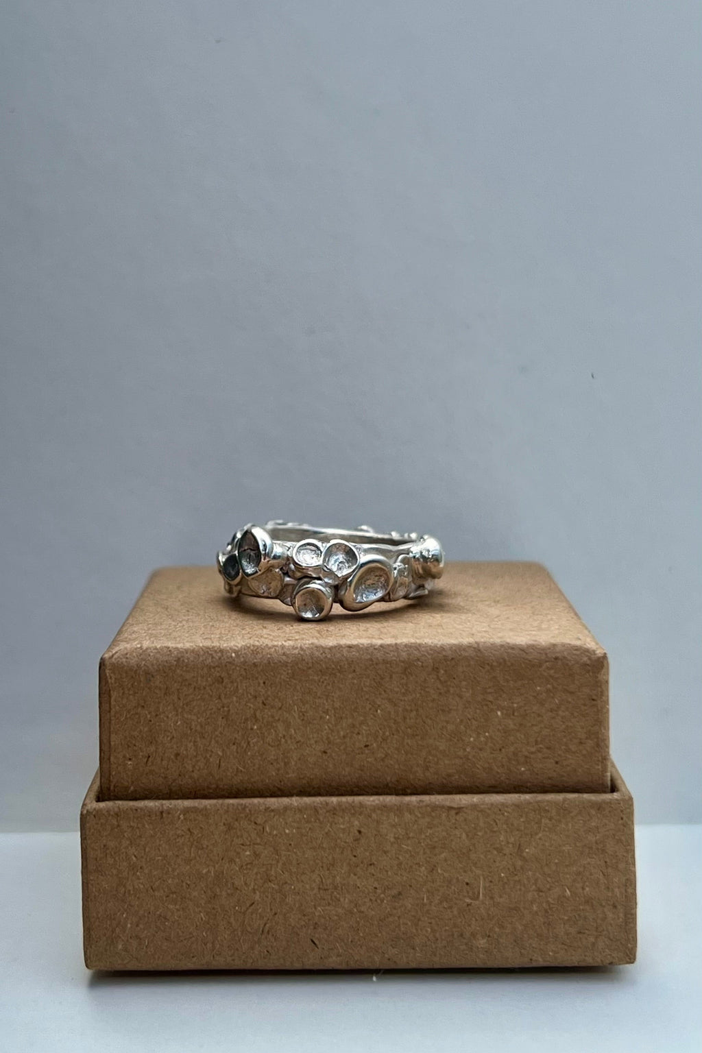 Silver ring on a brown box against a gray background