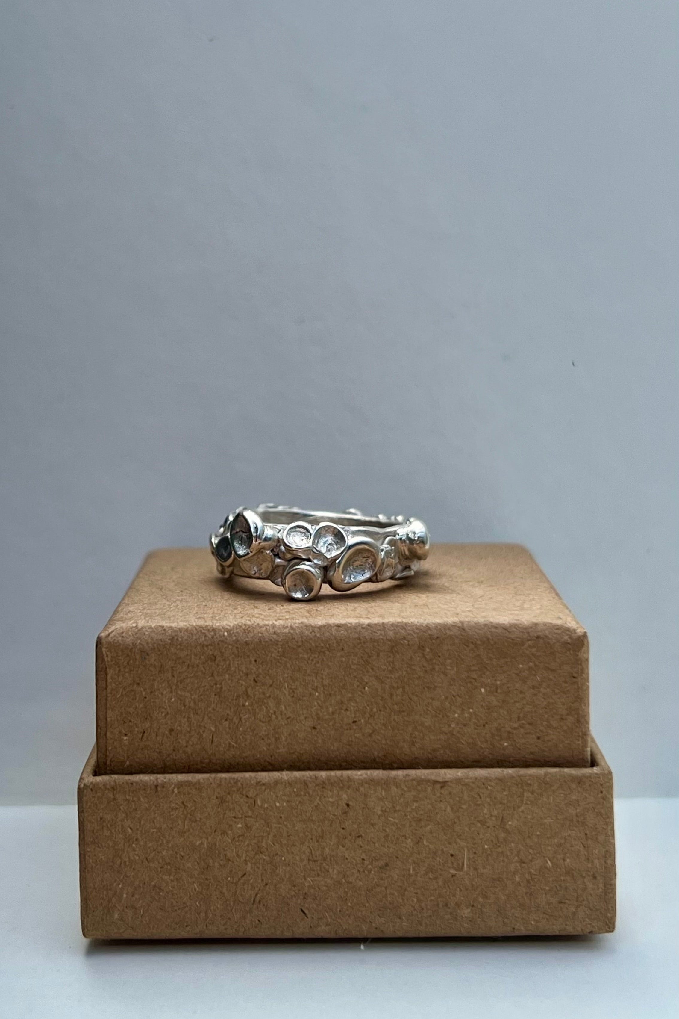 Silver ring on a brown box against a gray background