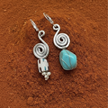 Silver earrings with turquoise stone on a brown textured surface