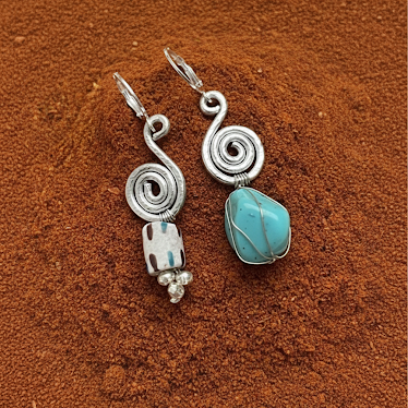 Silver earrings with turquoise stone on a brown textured surface