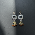 Pair of silver earrings with circular designs and orange beads on a dark gray background