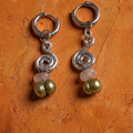 Pair of silver earrings with green beads on an orange textured background