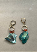 Pair of earrings with teal stone drops on a gray background