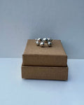 Silver ring on a cardboard box against a plain background
