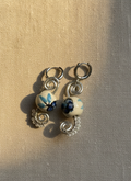 Pair of earrings with ceramic beads on a textured beige surface