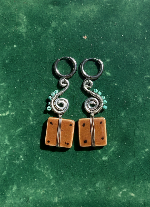 Pair of earrings on a green textured surface