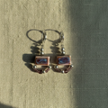 Pair of earrings with square designs on a textured fabric background